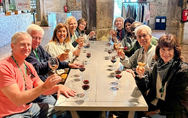 Guests seated at a long table enjoying a wine tasting experience indoors.