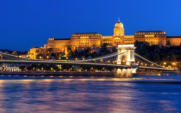 Hungarian Parliament and Chain Bridge illuminated at night, viewed from Danube River cruise in Budapest.
