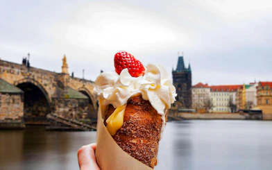Trdelník with whipped cream and strawberry in front of Charles Bridge, Prague Old Town.
