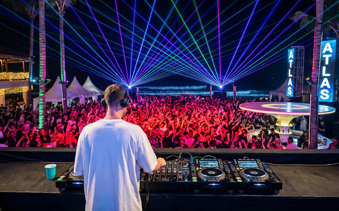 DJ performing at New Year Eve party with crowd and laser lights at Atlas Beach Club.