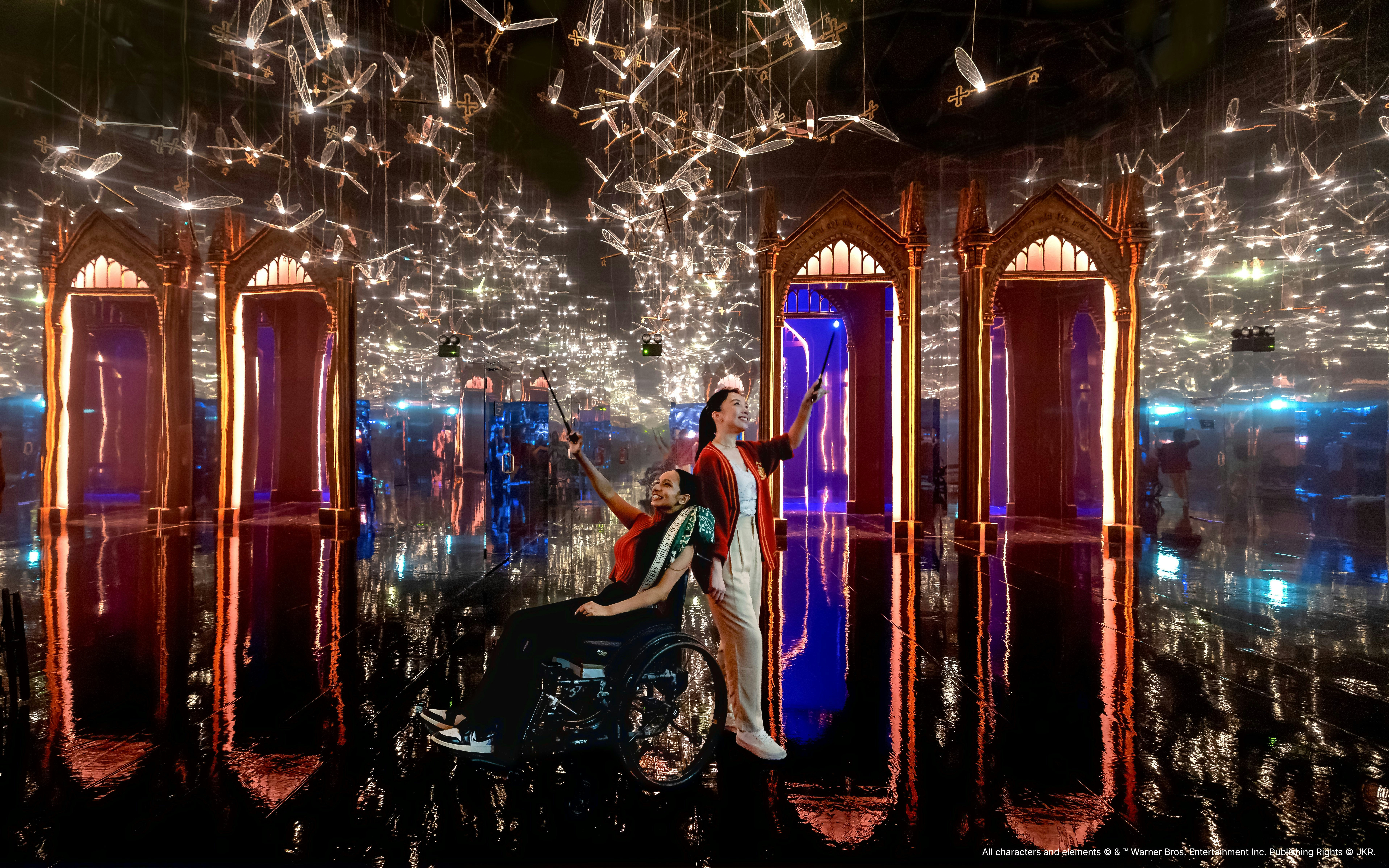 Visitors with wands in a mirrored room with flying keys at Harry Potter: Visions of Magic exhibit.