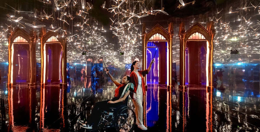 Visitors with wands in a mirrored room with flying keys at Harry Potter: Visions of Magic exhibit.