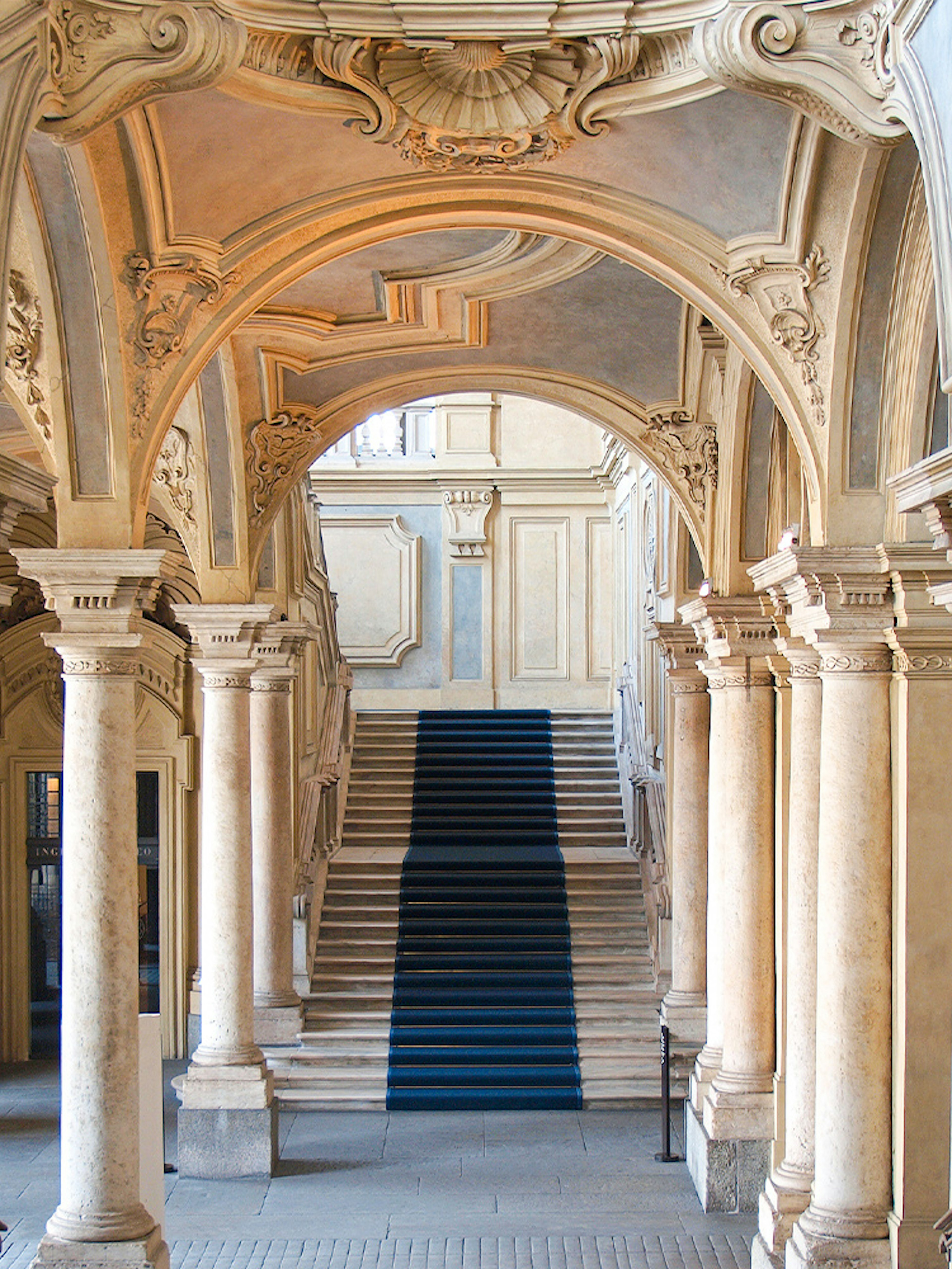 Grand staircase and ornate arches in a historic Turin palace, Italy.