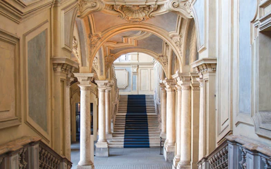 Grand staircase and ornate arches in a historic Turin palace, Italy.