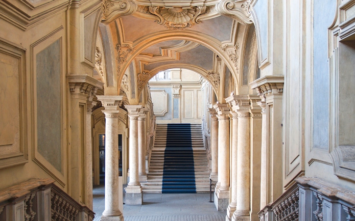 Grand staircase and ornate arches in a historic Turin palace, Italy.