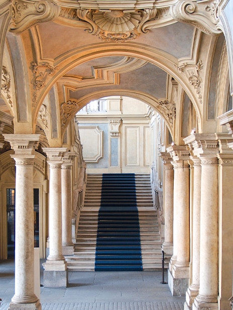Grand staircase and ornate arches in a historic Turin palace, Italy.