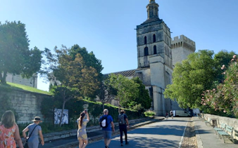Visitors walking towards the Papal Palace in Avignon, France.