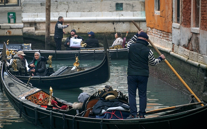 Gondola ride through Venice canal during Carnival with passengers and gondolier.