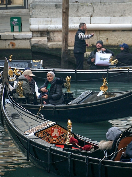 Gondola ride through Venice canal during Carnival with passengers and gondolier.