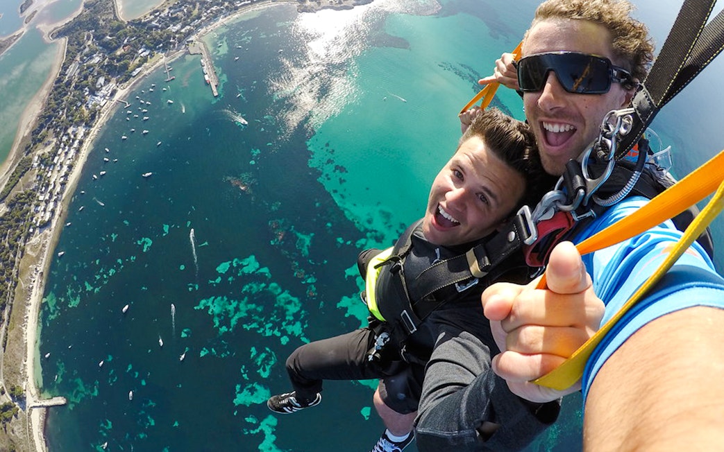 Tandem skydivers smiling during freefall over Rottnest Island, Australia.