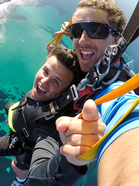 Tandem skydivers smiling during freefall over Rottnest Island, Australia.
