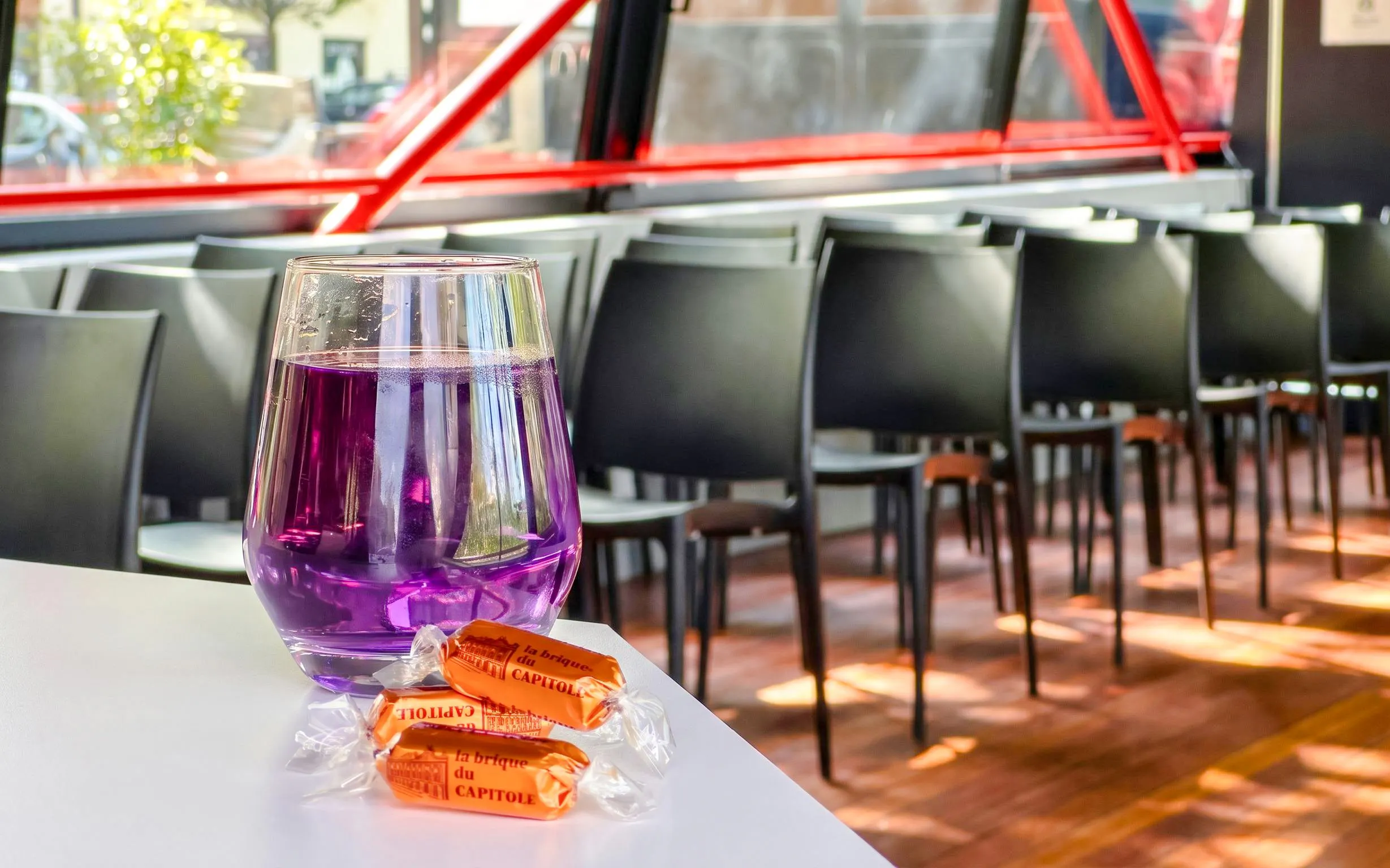 Purple drink and local candies on a table inside a Toulouse Canal du Midi cruise boat.