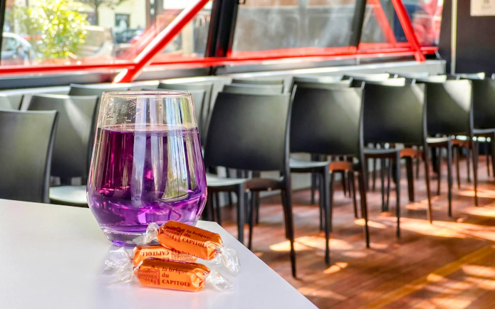 Purple drink and local candies on a table inside a Toulouse Canal du Midi cruise boat.