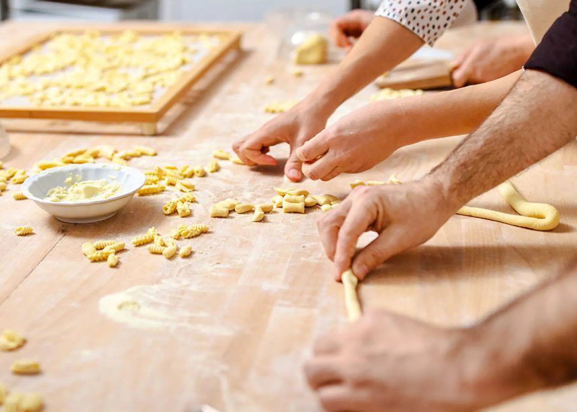 Hands shaping pasta dough during a Genoese cooking lesson in Genoa.