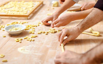 Hands shaping pasta dough during a Genoese cooking lesson in Genoa.