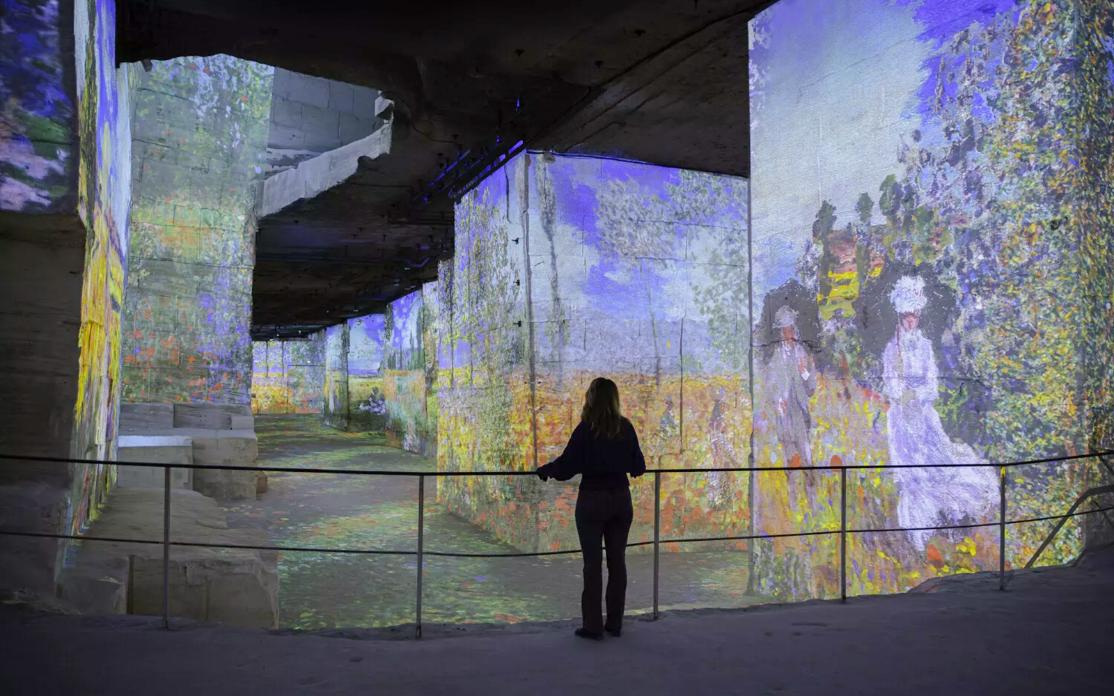 Monet projections at Carrières des Lumières, woman observing immersive art display.