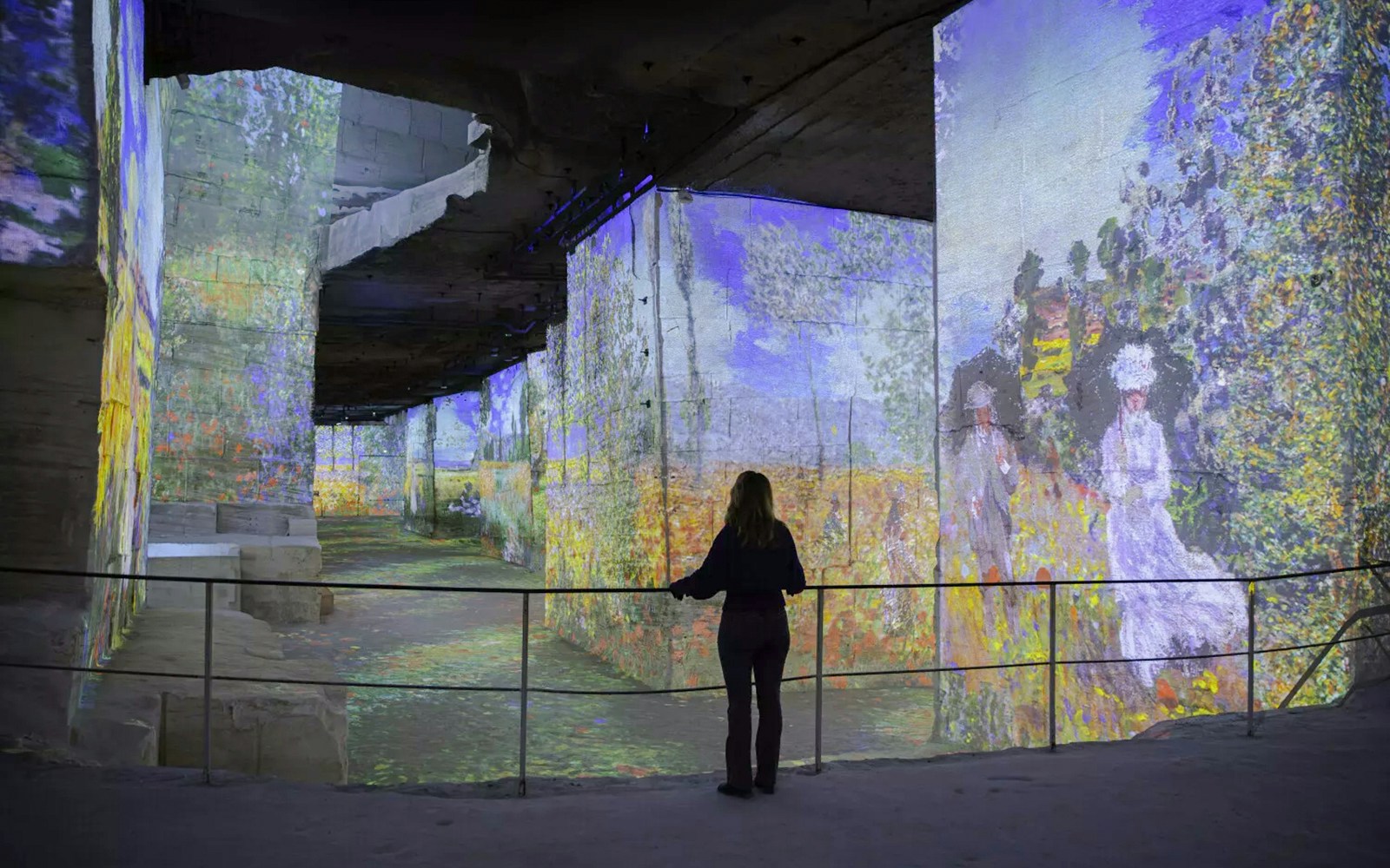 Monet projections at Carrières des Lumières, woman observing immersive art display.