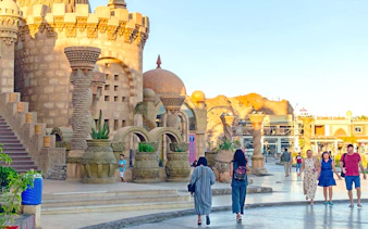 Sharm El-Sheikh cityscape with tourists walking near a mosque and shops.