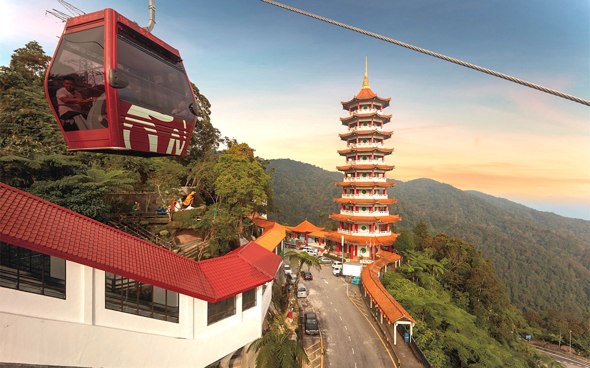 Genting Awana SkyWay cable car near pagoda tower in lush mountain landscape.
