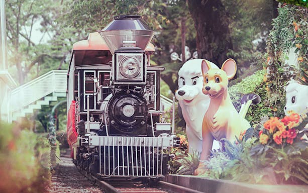 Train ride at Seibuen Amusement Park with animal statues and lush greenery.