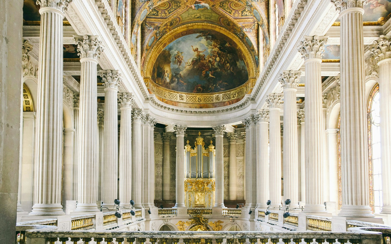 Royal Chapel of Versailles interior with ornate ceiling and stained glass windows.
