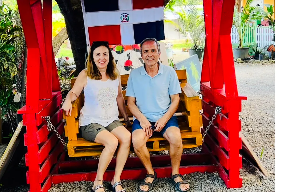 Couple sitting on a swing under Dominican flag at Punta Cana craft market.