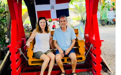 Couple sitting on a swing under Dominican flag at Punta Cana craft market.