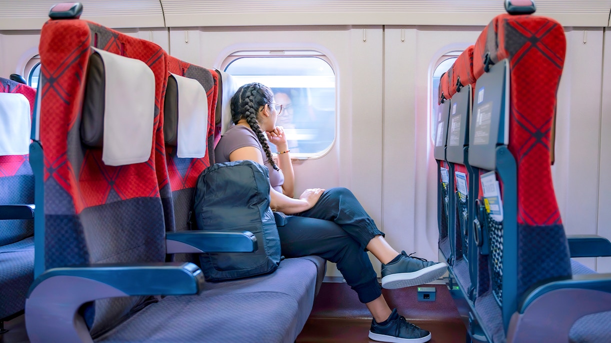 Girl looking out window on train, scenic countryside view.