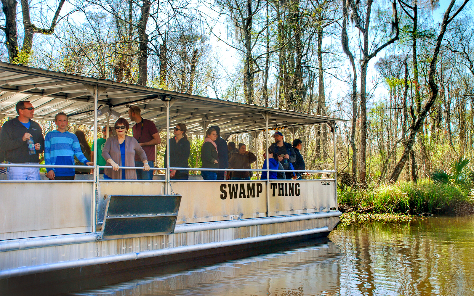 Tourists on a boat during a Swamp Tour near Oak Alley Plantation, surrounded by trees and water.