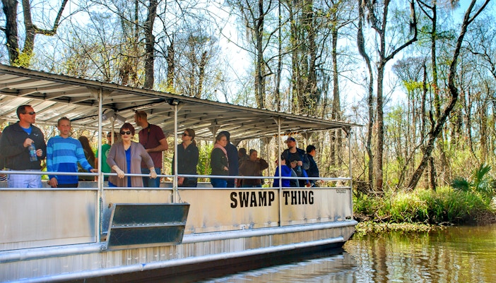 Tourists on a boat during a Swamp Tour near Oak Alley Plantation, surrounded by trees and water.