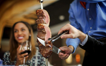 Server slicing meat at a Brazilian steakhouse in Rio de Janeiro.