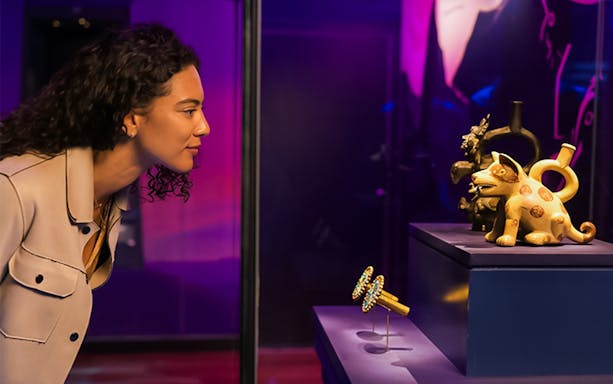 Visitor observing Andean ceramics and jewelry in a museum exhibit.