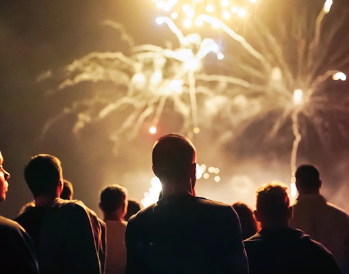 Crowd watching fireworks display at night.