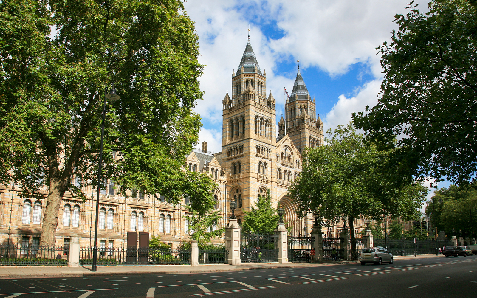 Natural History Museum London exterior with visitors and iconic Romanesque architecture.