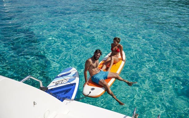 Guests relaxing on paddleboards during catamaran cruise from Ierapetra to Chrissi Island.