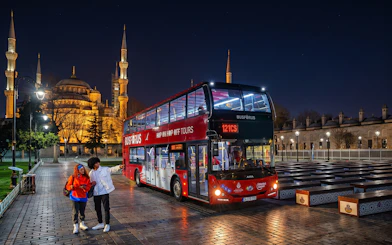 Hop On Hop Off Istanbul bus at night near illuminated mosque on Red Route.
