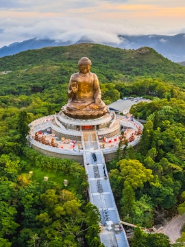 Tian Tan Buddha statue surrounded by lush hills in Hong Kong.