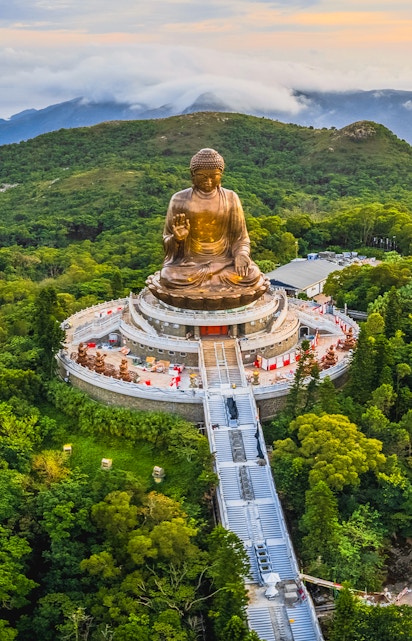 Tian Tan Buddha statue surrounded by lush hills in Hong Kong.