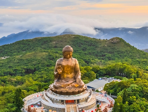 Tian Tan Buddha statue surrounded by lush hills in Hong Kong.