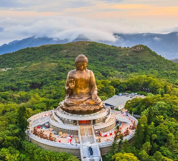 Tian Tan Buddha statue surrounded by lush hills in Hong Kong.