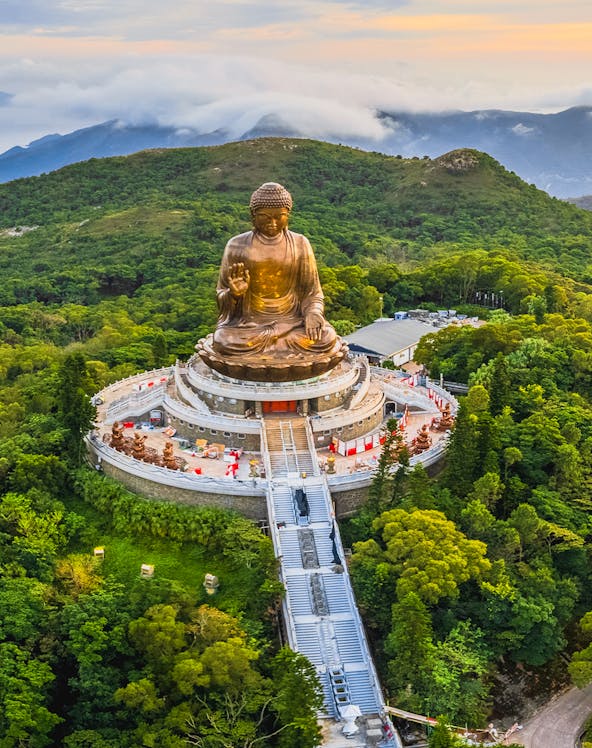 Tian Tan Buddha statue surrounded by lush hills in Hong Kong.