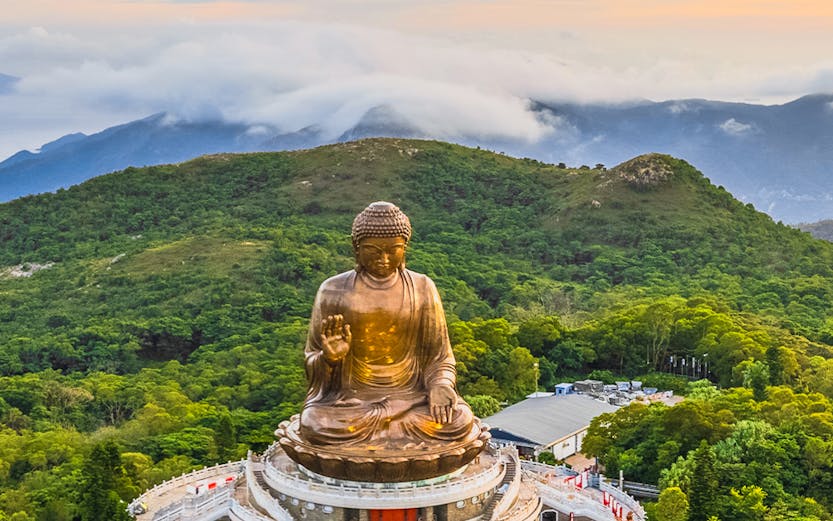 Tian Tan Buddha statue surrounded by lush hills in Hong Kong.