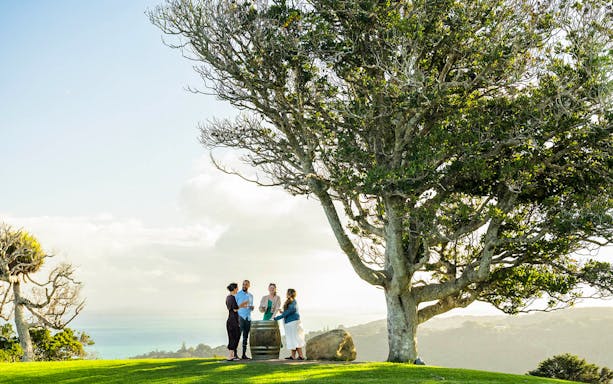 Friends enjoying wine at Batch Winery, Waiheke Island, with ocean view.