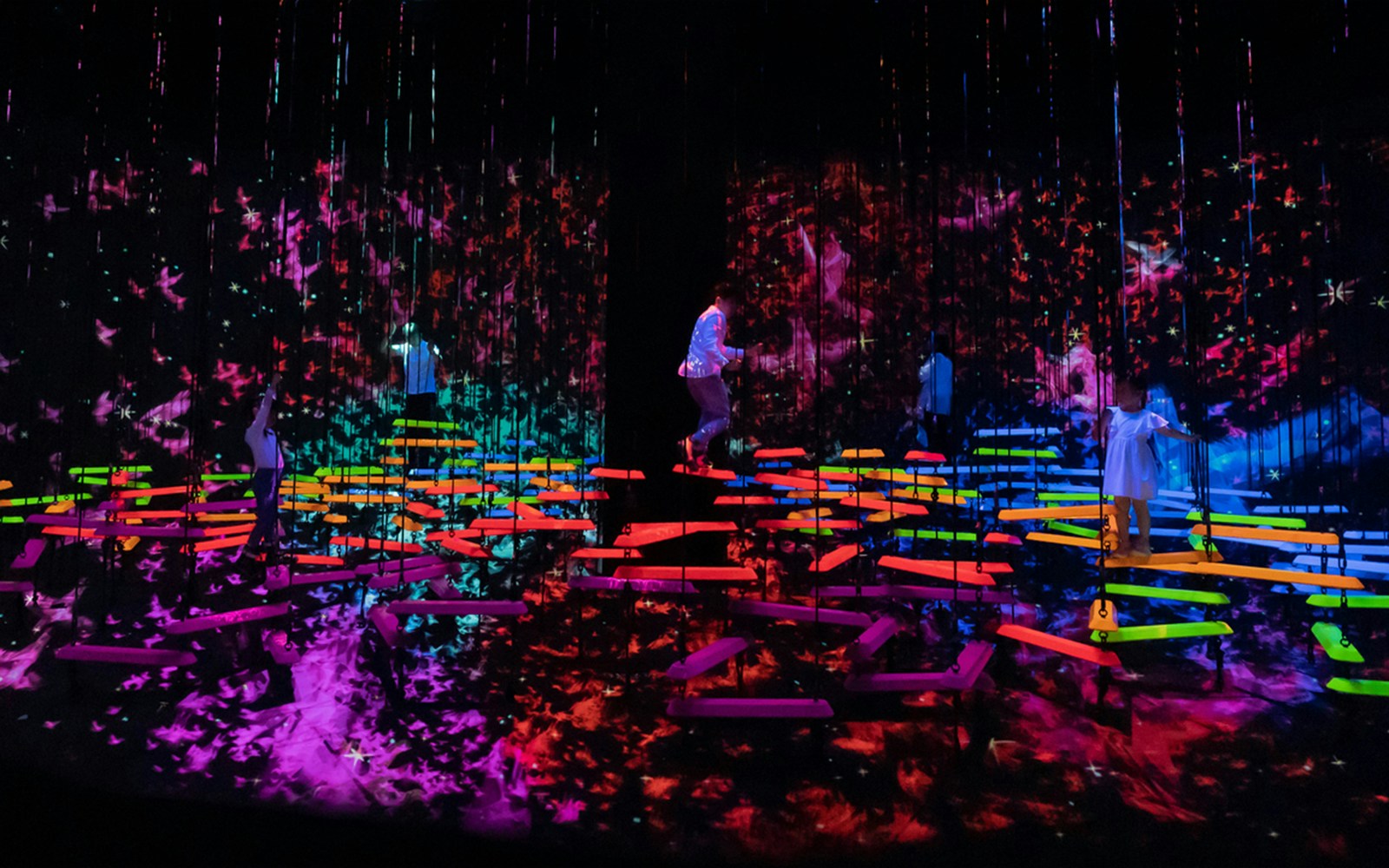 People explore vibrant digital art installations in a dark room.