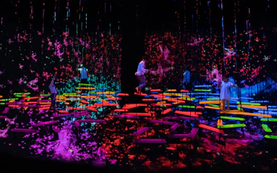People explore vibrant digital art installations in a dark room.