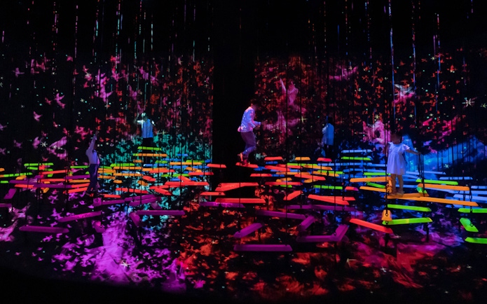 People explore vibrant digital art installations in a dark room.