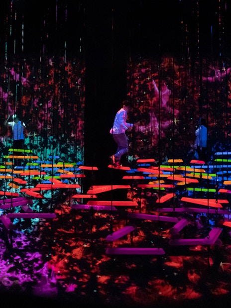 People explore vibrant digital art installations in a dark room.