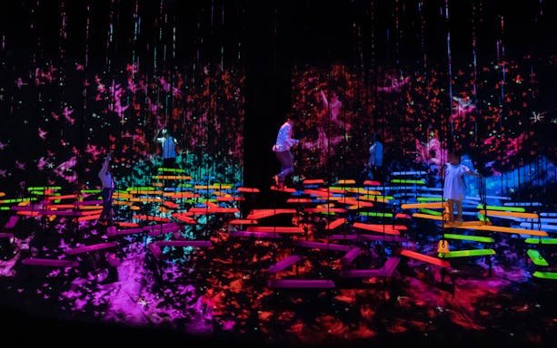 People explore vibrant digital art installations in a dark room.