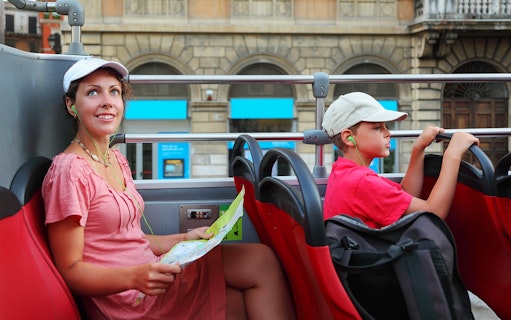 People enjoying a city tour on an open-top bus, listening to audio guides.
