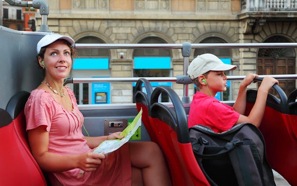 People enjoying a city tour on an open-top bus, listening to audio guides.